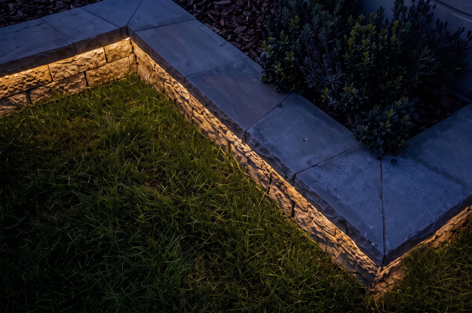 Warm LED strip lighting under a stone garden wall edge — retaining wall accent lighting
